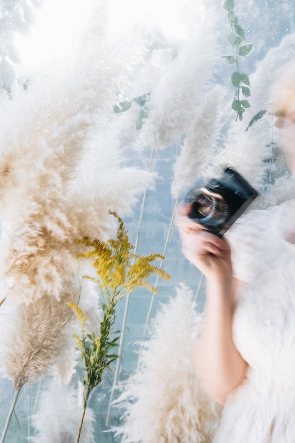 mulher de vestido branco segurando câmera preta