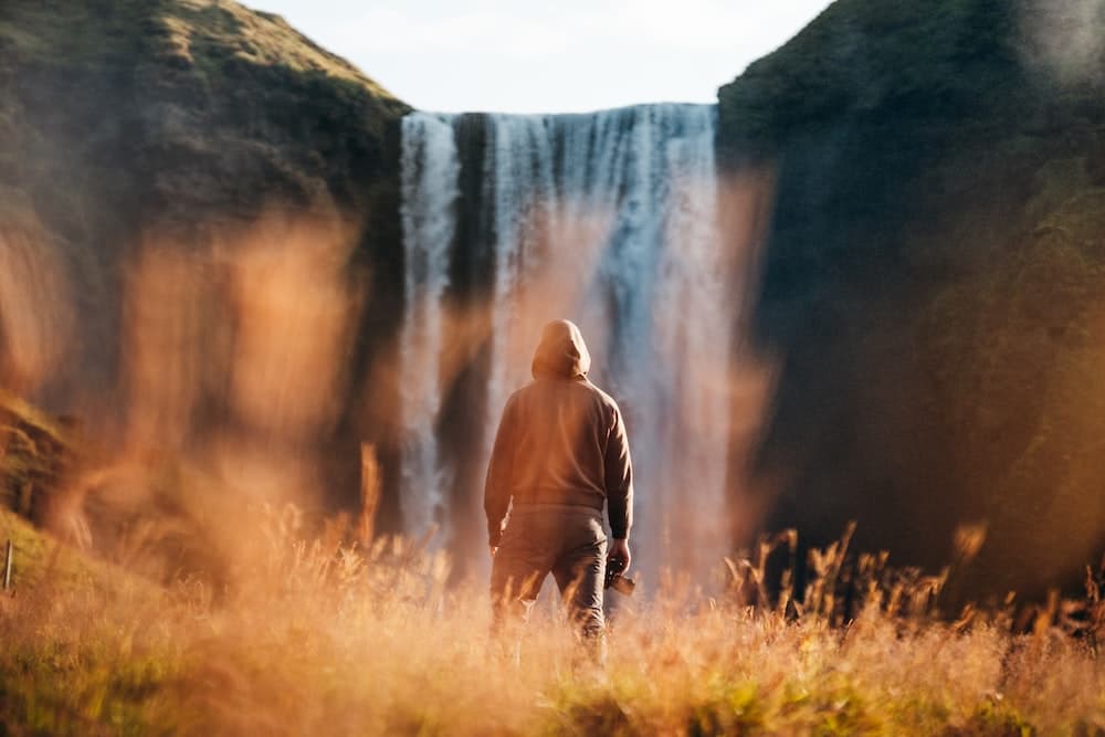 um homem parado em frente a uma cachoeira